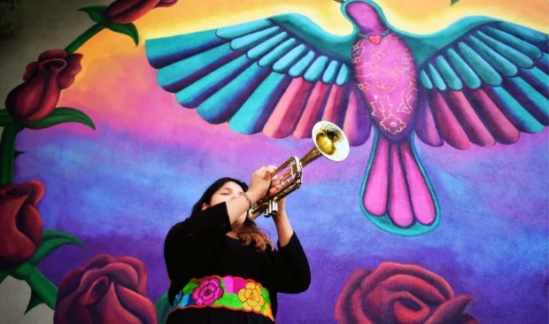 Estudiante de Harmony Project tocando la trompeta frente a un colorido mural de Phoenix