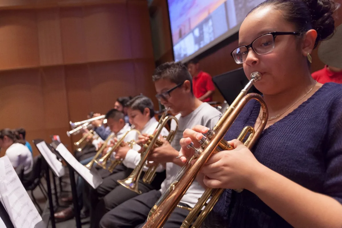 Young trumpet players rehearsing together with their sheet music.